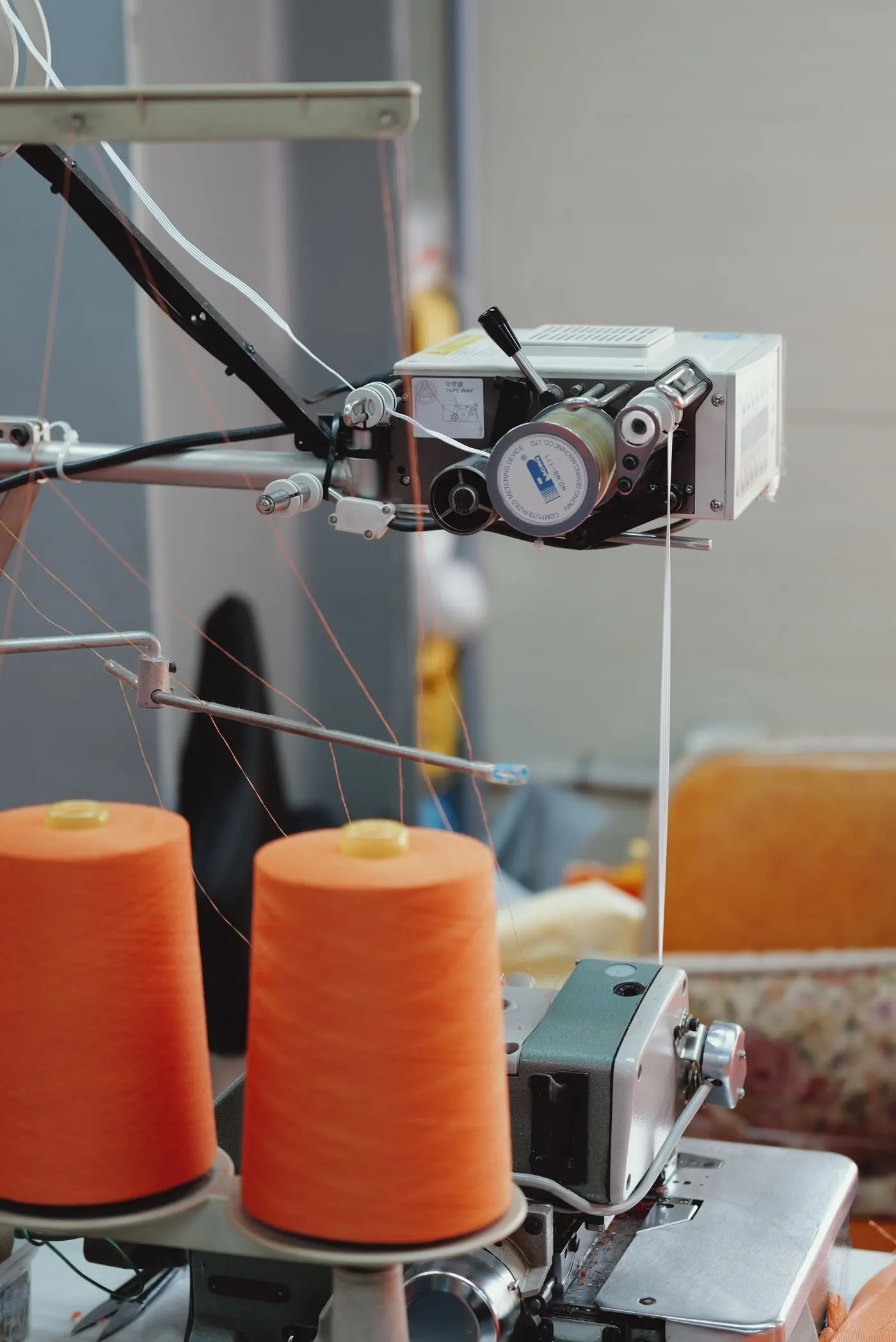 Cones de linha laranja montados na máquina de costura industrial da fábrica de camisetas