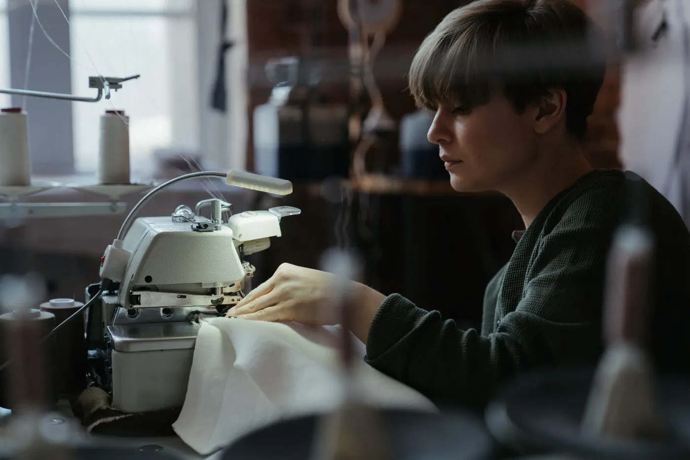 Costureira operando máquina overloque industrial montando uma camiseta na fábrica